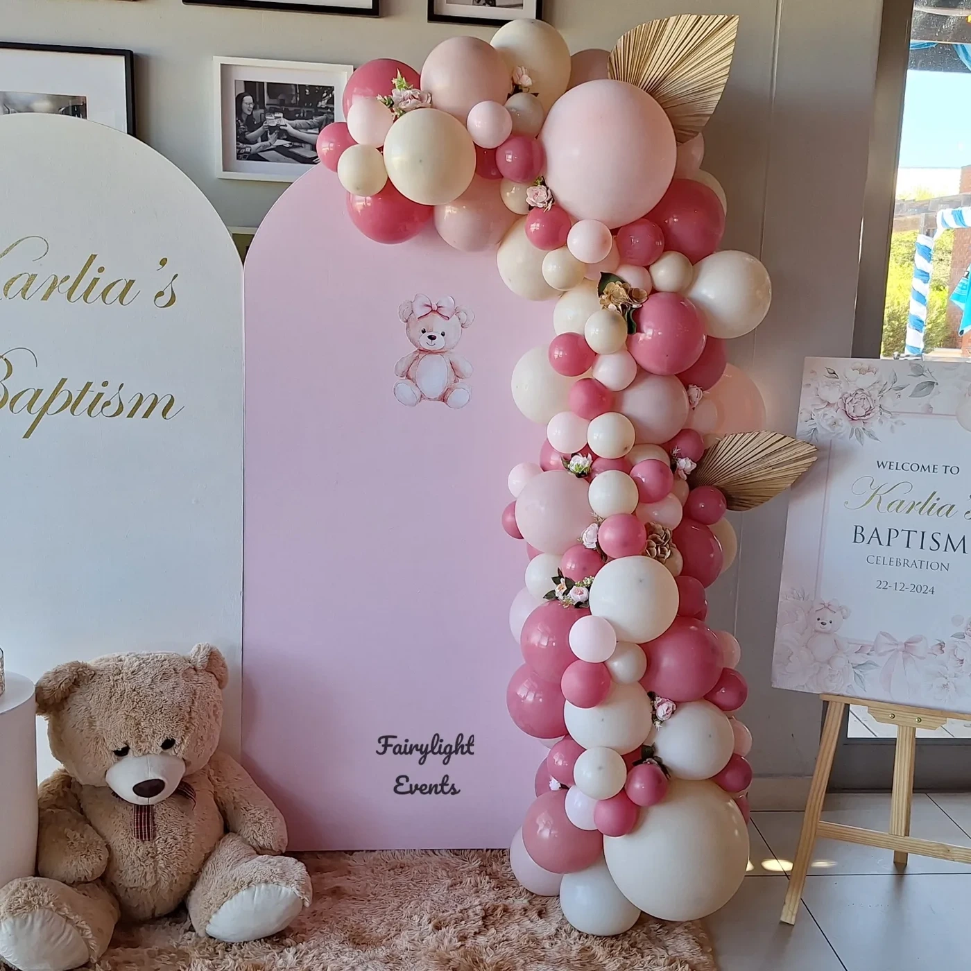 Pink balloon garland baptism backdrop with teddy bear